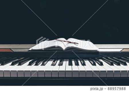Open notepad on piano keys in the dark, copy space. Open notepad on piano keys in the dark, copy space. 88957988