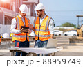 Engineer and architect discussing building plan at construction site. 88959749