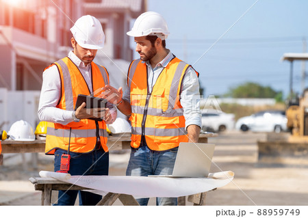 Engineer and architect discussing building plan at construction site. 88959749
