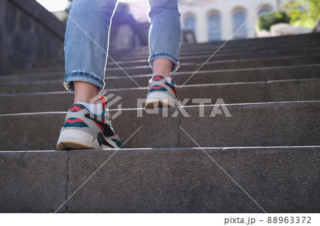 Female legs in sports sneakers going up stairs closeup Female legs in sports sneakers going up stairs closeup 88963372