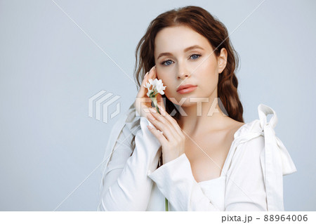 Girl with a white flower near her face. 88964006