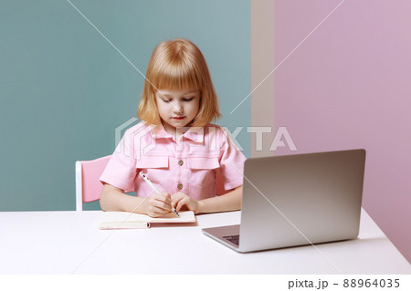 Little joyful girl sitting at a laptop Little joyful girl sitting at a laptop 88964035