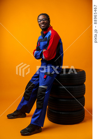 African american car service worker with car tyre against yellow background 88965467