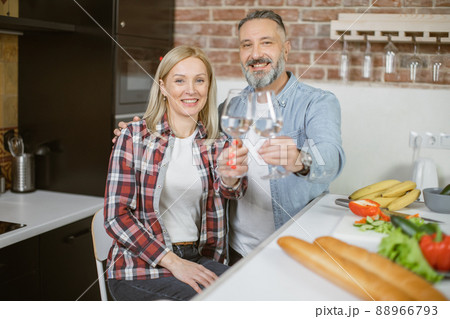 Mature couple sitting on kitchen with glasses of fresh water Mature couple sitting on kitchen with glasses of fresh water 88966793