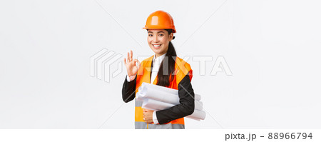 Confident successful female asian construction manager, architect in safety helmet and jacket, showing okay gesture and carry blueprints of building project, guarantee quality, white background Confident successful female asian construction manager, architect in safety helmet and jacket, showing okay gesture and carry blueprints of building project, guarantee quality, white background 88966794