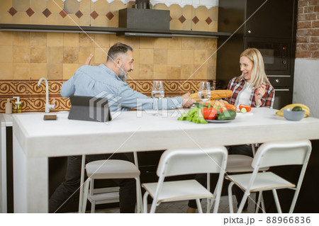 Couple using baguettes for playful fight on bright kitchen Couple using baguettes for playful fight on bright kitchen 88966836