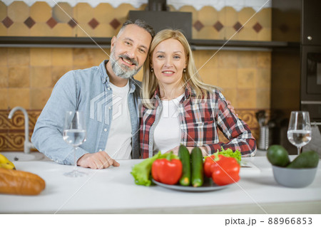 Portrait of mature couple posing in embrace on kitchen Portrait of mature couple posing in embrace on kitchen 88966853