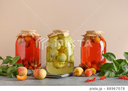 Three canned apple and cherry compote in large glass jars on gray table. 88967078