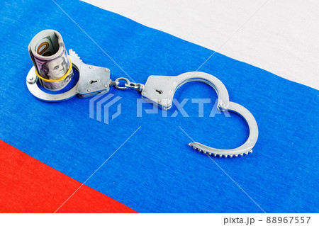 roll of us dollar banknotes in a handcuffs on flat full-frame russian flag roll of us dollar banknotes in a handcuffs on flat full-frame russian flag 88967557