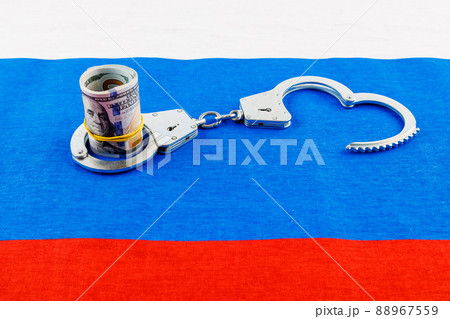 roll of us dollar banknotes in a handcuffs on flat full-frame russian flag roll of us dollar banknotes in a handcuffs on flat full-frame russian flag 88967559