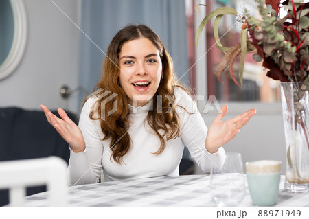 Portrait of positive woman sitting at table and gesticulating 88971949