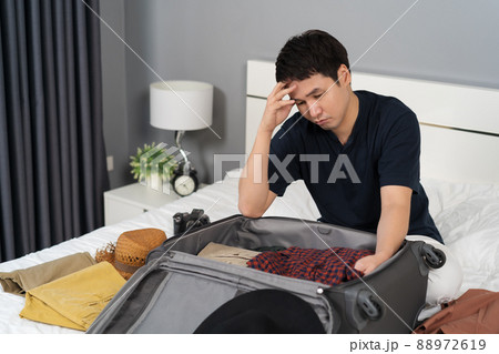 stressed man having problem with packing clothes into suitcase on bed, holiday travel concept stressed man having problem with packing clothes into suitcase on bed, holiday travel concept 88972619