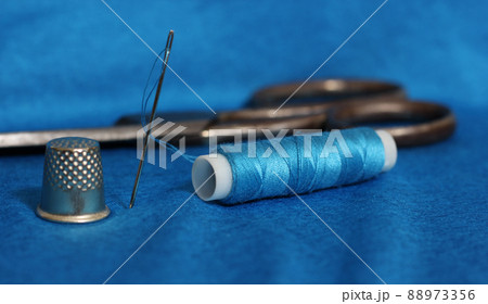 Spool of Blue Thread, Thimble and Needle on Blue Fabric Spool of Blue Thread, Thimble and Needle on Blue Fabric 88973356
