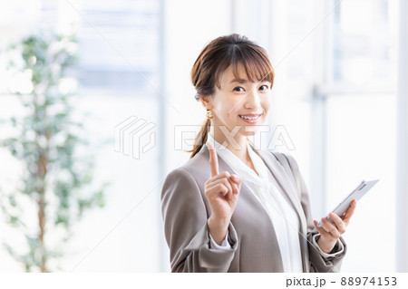 スマホを持って明るい窓辺に立つビジネスウーマン 88974153