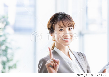 スマホを持って明るい窓辺に立つビジネスウーマン 88974155