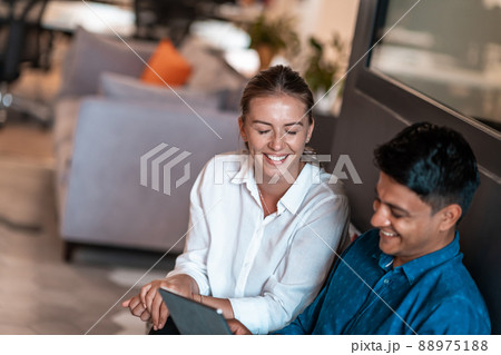 Multiethnic business people man with a female colleague working together on tablet computer in relaxation area of modern startup office Multiethnic business people man with a female colleague working together on tablet computer in relaxation area of modern startup office 88975188