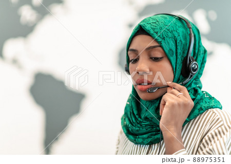 Muslim female with green hijab scarf customer representative business woman with phone headset helping and supporting online with customer in modern call centre Muslim female with green hijab scarf customer representative business woman with phone headset helping and supporting online with customer in modern call centre 88975351