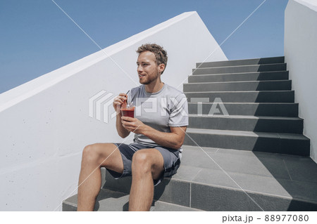Man drinking healthy smoothie detox juice post cardio workout at gym stairs. Runner athlete living an active lifestyle 88977080