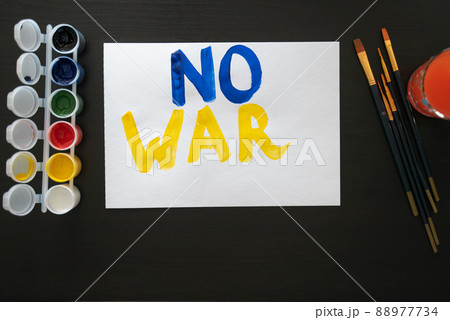 Man paints poster for rally with the slogan NO TO WAR. With brush and paints, he prints colorful bright letters on sheet. Person's requirement. Poster with call, rally, picket, march, protest, action Man paints poster for rally with the slogan NO TO WAR. With brush and paints, he prints colorful bright letters on sheet. Person's requirement. Poster with call, rally, picket, march, protest, action 88977734