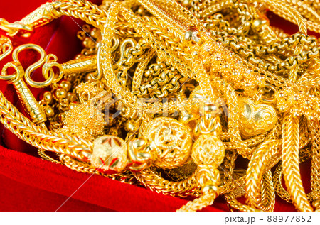 Many gold necklaces in a red velvet box on red background. 88977852