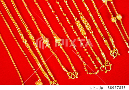 Set of gold necklace on red Velvet fabric. 88977853
