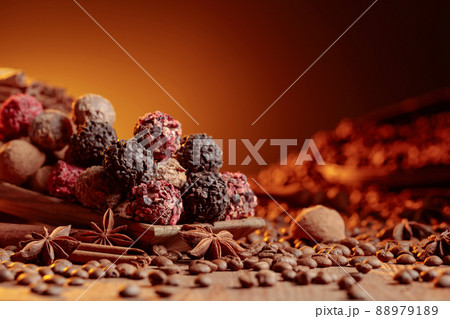 Chocolate truffles with cinnamon, anise, and coffee beans on a wooden table. 88979189