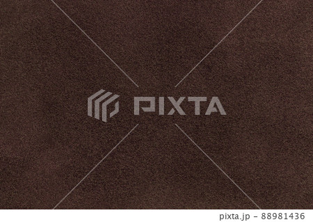Background of dark brown suede matte fabric. Velvet matt texture of umber nubuck textile. Velveteen pattern. Background of dark brown suede matte fabric. Velvet matt texture of umber nubuck textile. Velveteen pattern. 88981436