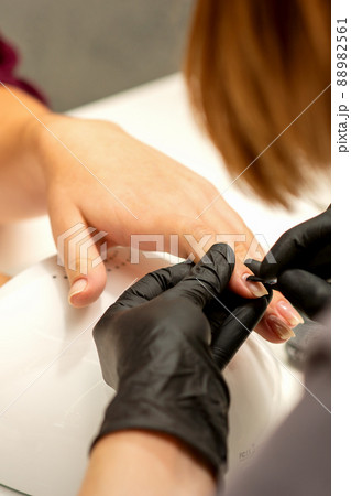 Manicure painting process. Manicure master paint the nails with transparent varnish in a nail salon, close up Manicure painting process. Manicure master paint the nails with transparent varnish in a nail salon, close up 88982561