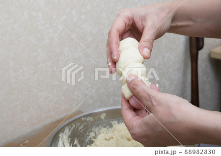 Women's hands carefully hold a sausage wrapping it in dough in the home kitchen. The process of preparing a hot dog close-up. Women's hands carefully hold a sausage wrapping it in dough in the home kitchen. The process of preparing a hot dog close-up. 88982830