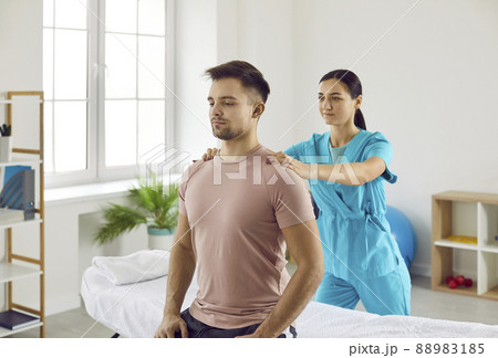 Specialist at physical therapy and rehabilitation clinic massaging young man's shoulders 88983185