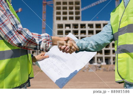 two engineers, a man and a woman in white helmets and protective vests, work at the construction site. two engineers, a man and a woman in white helmets and protective vests, work at the construction site. 88985586