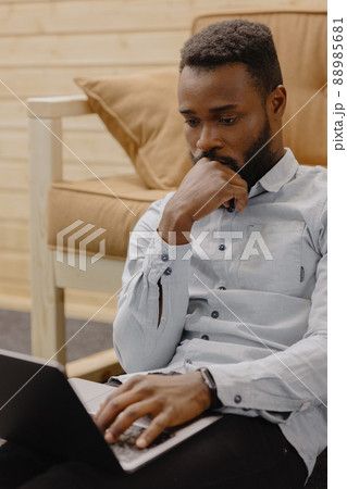 a handsome and young African American man in an office or coworking works on a laptop 88985681