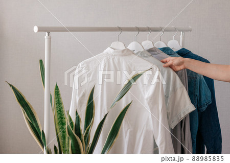 a woman's hand holding clothes on a hanger, a rail or Wardrobe in the living room a woman's hand holding clothes on a hanger, a rail or Wardrobe in the living room 88985835