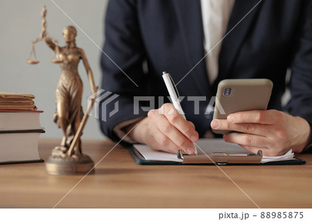 selective focus, female lawyer or judge checks documents or a contract and makes notes in a notebook and phone, is engaged in the registration of divorce proceedingss or contracts via the Internet selective focus, female lawyer or judge checks documents or a contract and makes notes in a notebook and phone, is engaged in the registration of divorce proceedingss or contracts via the Internet 88985875