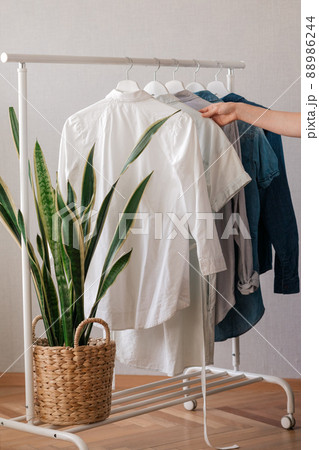 a woman's hand holding clothes on a hanger, a rail or Wardrobe in the living room a woman's hand holding clothes on a hanger, a rail or Wardrobe in the living room 88986244