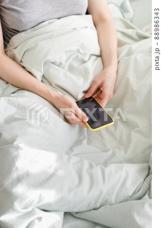 good morning, sunny day, caucasian woman checking messages, holding a yellow phone in her hand good morning, sunny day, caucasian woman checking messages, holding a yellow phone in her hand 88986343
