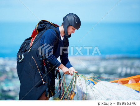 Is everything tight enough. Shot of a man getting ready to go paragliding. Is everything tight enough. Shot of a man getting ready to go paragliding. 88986346