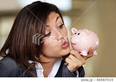 Cash is a girls best friend. An attractive businesswoman pulling a kissing face at her piggybank. 88987019