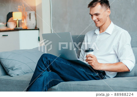 young man with a hot drink browsing the news on the Internet . young man with a hot drink browsing the news on the Internet . 88988224