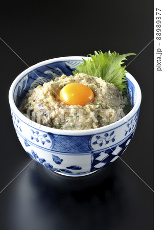 卵の黄身がトッピングされてる鯵のなめろう丼を黒背景で撮影 88989377