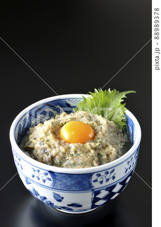 卵の黄身がトッピングされてる鯵のなめろう丼を黒背景で撮影 88989378