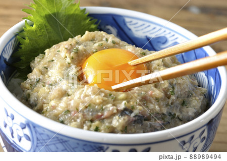 鯵のなめろう丼にトッピングされている卵黄を箸で割って食す 鯵のなめろう丼にトッピングされている卵黄を箸で割って食す 88989494