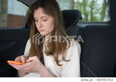 Female passenger in the car looks and types in the phone. Social Media in transportation Female passenger in the car looks and types in the phone. Social Media in transportation 88990703