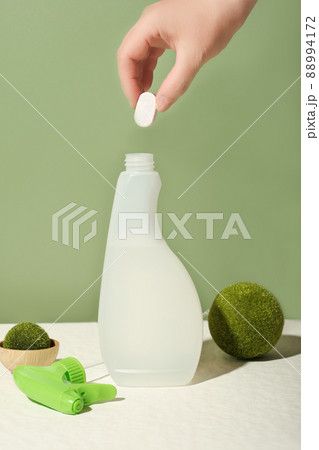 hand holding dissoluble tablet for kitchen cleanser refill. bottle of cleansing spray refilling. zero waste, refillable system. eco-friendly housekeeping. hand holding dissoluble tablet for kitchen cleanser refill. bottle of cleansing spray refilling. zero waste, refillable system. eco-friendly housekeeping. 88994172