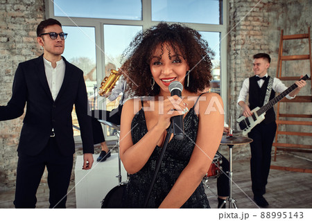 Repetition of multi ethnic jazz band in loft. Bass guitar player, electric guitar player, saxophonist and drummer at loft. Jazz music and jam session concept. passion for music and youth culture 88995143