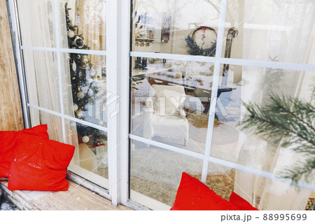 Cozy house with big windows and decorated Christmas tree. Patio at snowy winter evening Cozy house with big windows and decorated Christmas tree. Patio at snowy winter evening 88995699