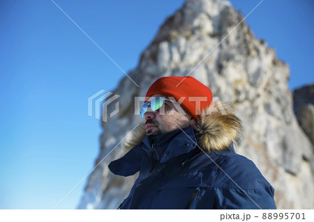 Portrait of the man tourist in red cap and blue jacket wearing sunglasses on ice Portrait of the man tourist in red cap and blue jacket wearing sunglasses on ice 88995701