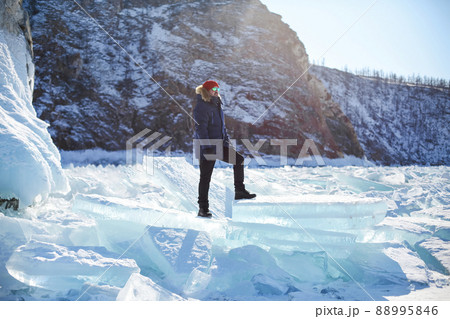 Portrait of the man tourist in red cap and blue jacket wearing sunglasses on ice 88995846