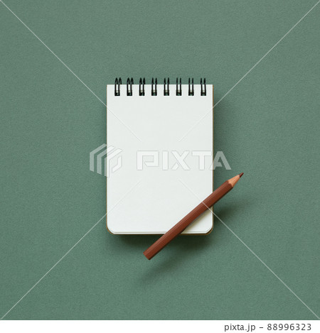 Empty memo note pad with brown pencil on green background. top view, copy space Empty memo note pad with brown pencil on green background. top view, copy space 88996323