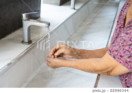 Asian senior or elderly old lady woman patient washing hand by soap and clean water for protect safety infection and kill Coronavirus Covid-19 virus, bacteria and germs. 88996344